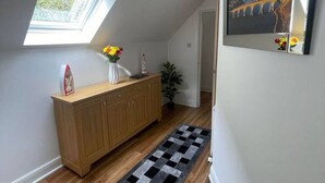 A hallway with a wooden cabinet, a black and white rug, a skylight, and a framed picture on the wall.