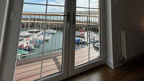 A room with a large sliding glass door leading to a balcony with a view of a marina.