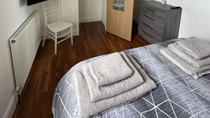 A bedroom with a bed, a chair, a dresser, a television, and a wardrobe.