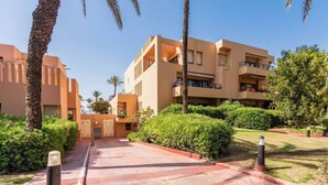 A modern building with multiple balconies and a paved walkway. - Sotogrande Beach Apartment (San Roque)