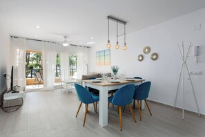 A modern dining area with a white table, blue chairs, and pendant lighting.