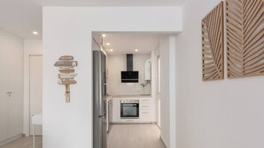 A modern kitchen with white cabinets, a built-in oven, and a stainless steel refrigerator. - Sotogrande Beach Apartment (San Roque)