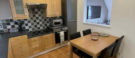 A compact kitchen with a microwave, refrigerator, and wooden cabinets.
