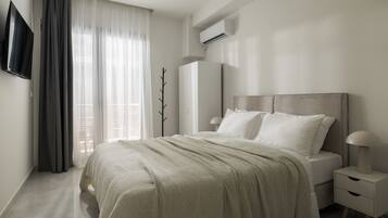A modern bedroom with a bed, bedside tables, a TV, and an air conditioning unit.