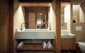 A modern bathroom with a large granite sink, wooden accents, and a mirror reflecting the space. - Olympus Refuge D (Dio-Olympos)