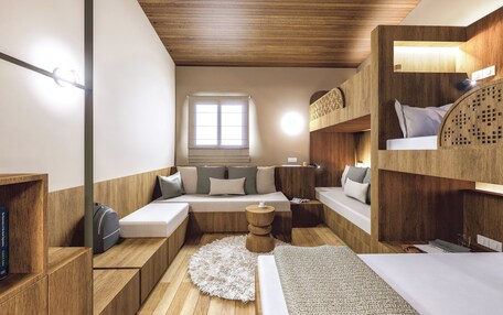 A compact room with bunk beds, a sofa, a small round table, and a window.