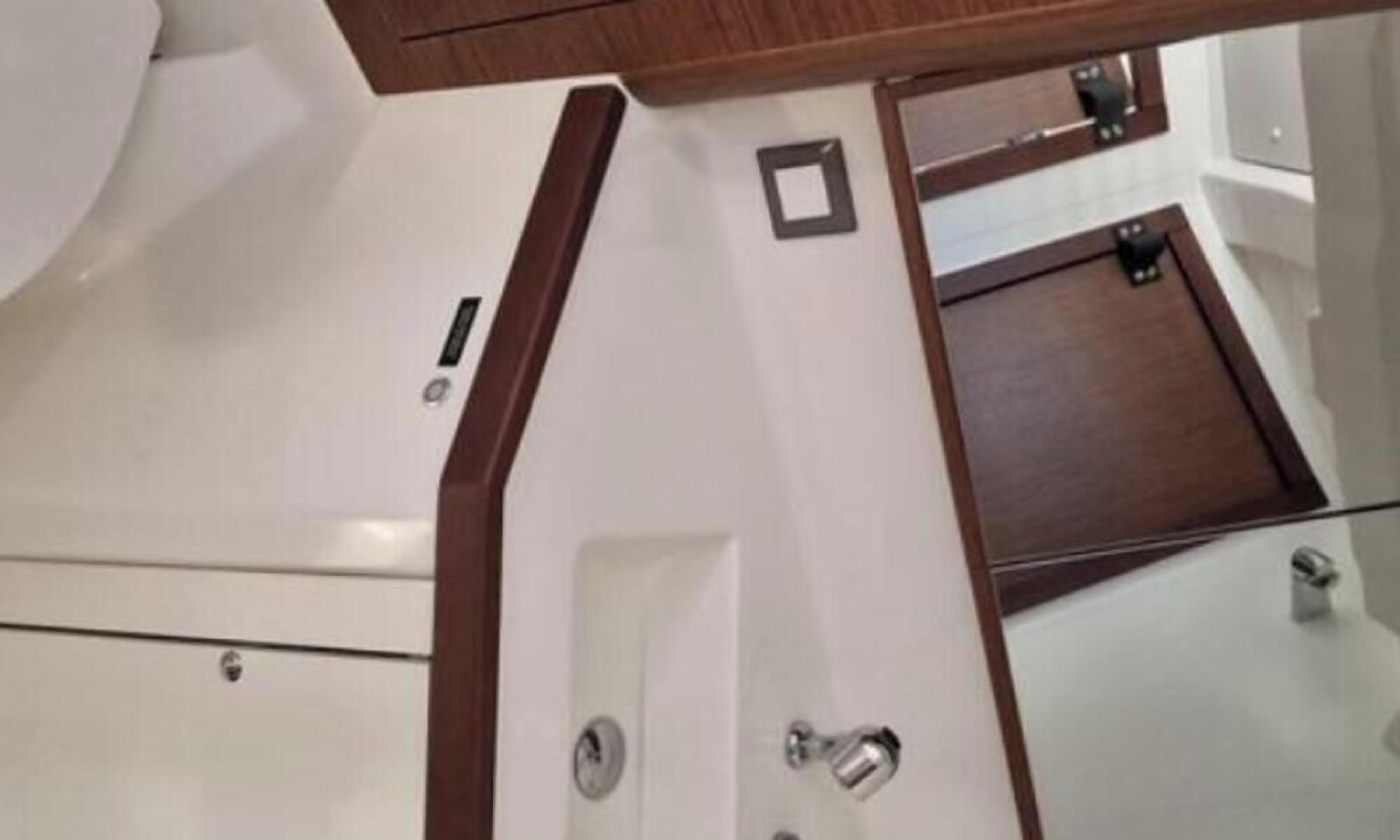 A bathroom with a white sink, a mirror, and a wooden vanity.
