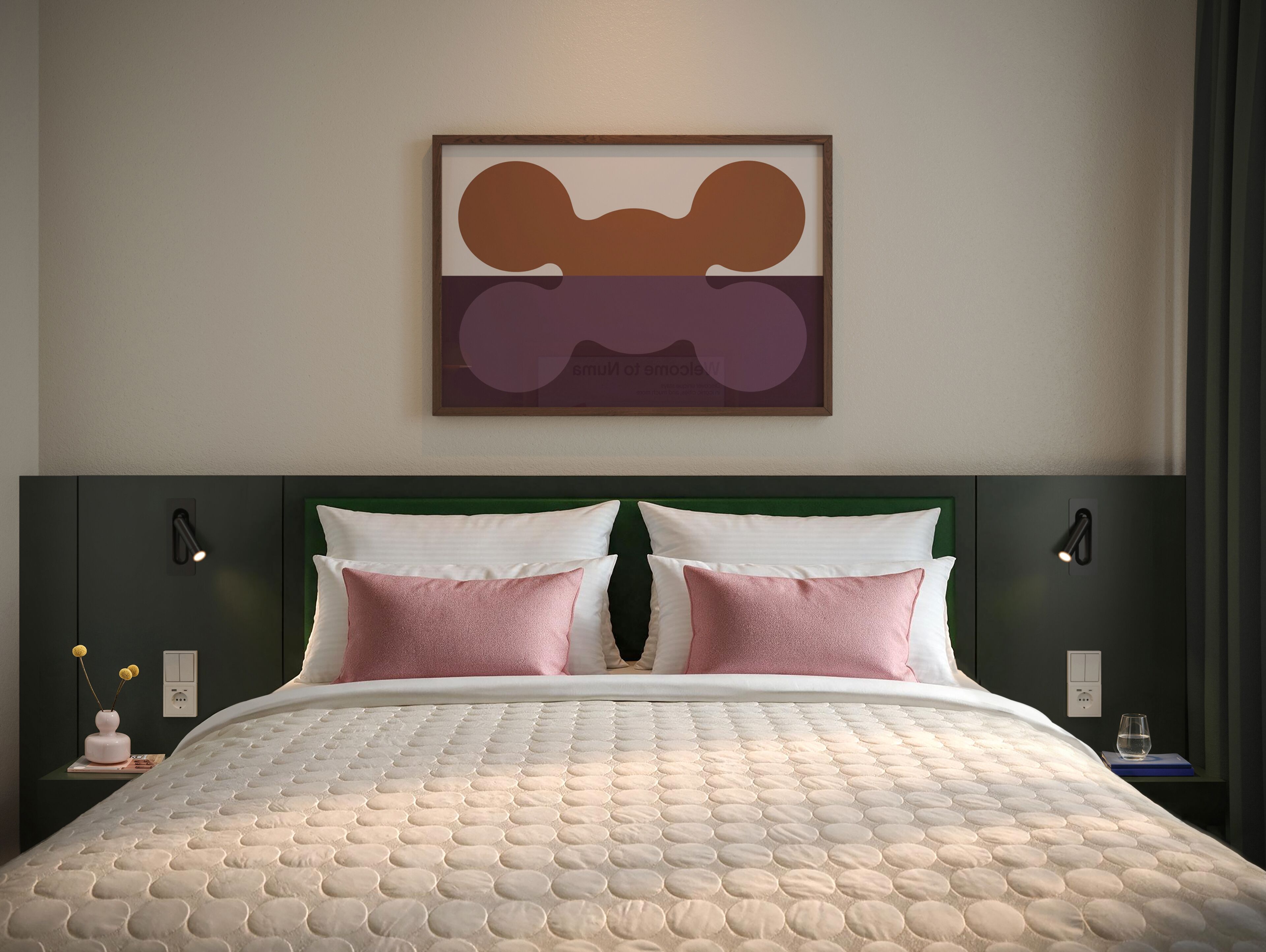 Un lit recouvert d’une courtepointe, deux oreillers, une tête de lit verte et un tableau abstrait accroché au mur.