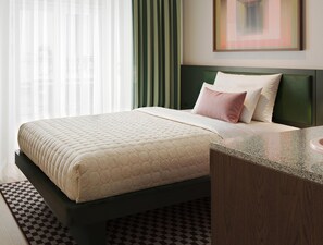 A hotel room with a bed, a bedside table, a checkered rug, and a painting on the wall. - Numa Milan Manfredo (Milan)