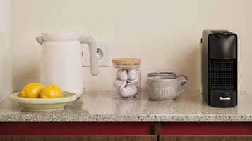 Una encimera de cocina con cafetera, hervidor, taza y limones en un plato.