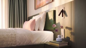 A neatly made bed with pillows, a bedside table with a book and a vase of flowers, and a wall-mounted light switch. - Numa Milan Manfredo (Milan)