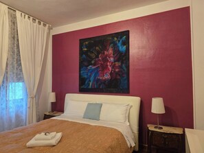 A hotel room with a bed, a nightstand, a lamp, and a painting on the wall. - Maison Galliano  Verona (Verona)