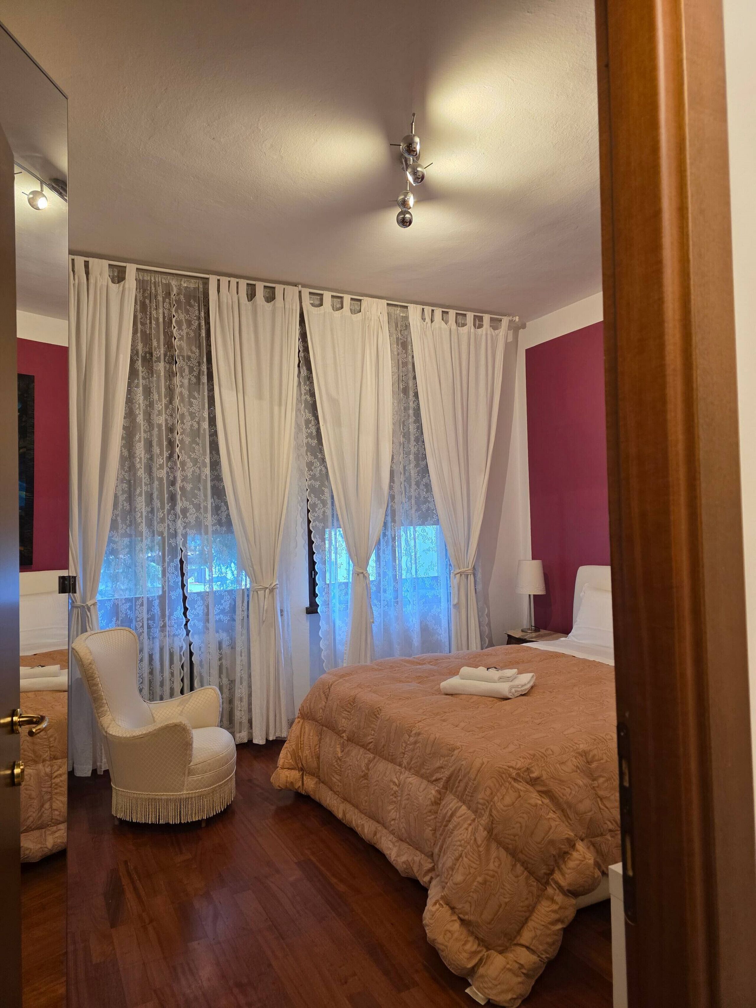 A hotel room with a bed, a chair, curtains, and a window.