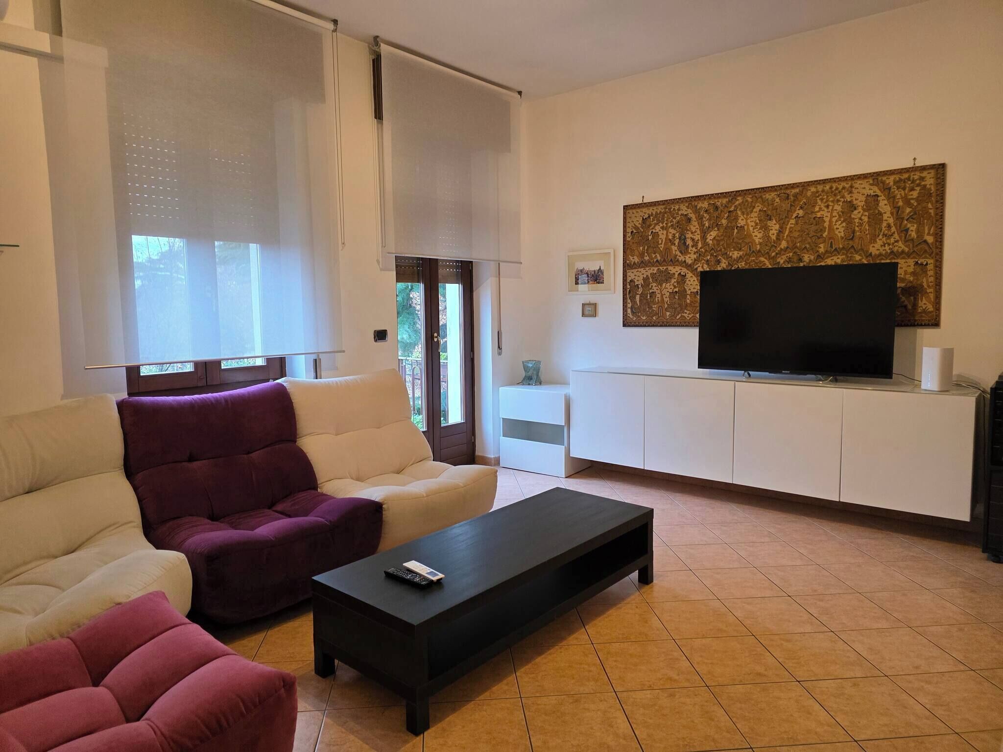 Una sala de estar moderna con un sofá, un sillón, una mesa de centro, un televisor y una obra de arte en la pared.