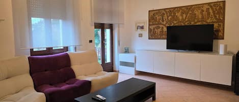 A modern living room with a sofa, armchair, coffee table, TV, and artwork on the wall.
