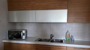 Cuina amb armaris de fusta, microones, rentapelats i escorredora.