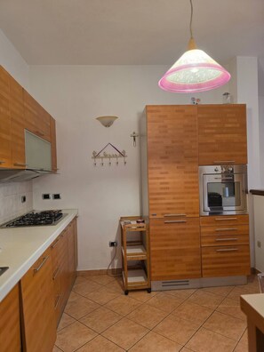 A kitchen with wooden cabinets, a gas stove, a built-in oven, and a hanging light fixture. - Maison Galliano  Verona (Verona)