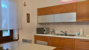 Una cuina moderna amb armaris de fusta, microones, rentavaixelles i taula de dinar amb cadires.