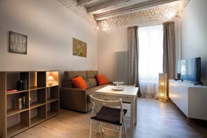 Ein modernes Wohnzimmer mit einer Couch, einem Esstisch, einem Fernseher und einem Bücherregal.