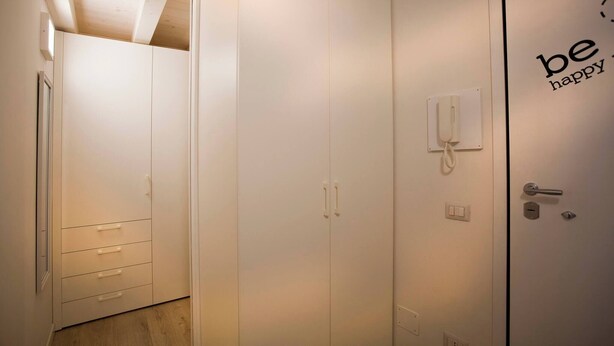 Habitación de hotel con armario, teléfono en la mesita de noche y puerta con picaporte y cerradura.