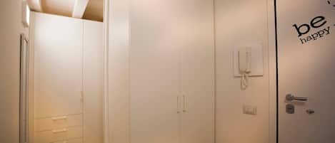 Habitación de hotel con armario, teléfono en la mesita de noche y puerta con picaporte y cerradura.