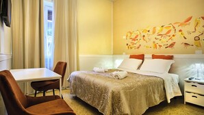 Ein Hotelzimmer mit einem Bett, einem Schreibtisch, einem Stuhl und einer Wand mit Vogelaufklebern.