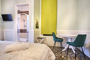 A hotel room with a bed, a shower, a TV, and a small table with chairs. - Stanza verde con bagno privato - uso cucina - La Voliera (Verona)