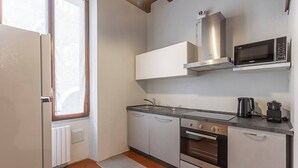 A compact kitchen with a built-in oven, microwave, and a window above the sink. - Maison Riva 12 Verona (Verona)