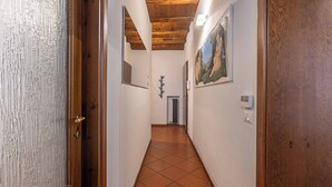 A hallway with a wooden ceiling, tiled floor, and a painting on the wall. - Maison Riva 12 Verona (Verona)