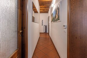 A hallway with a wooden ceiling, tiled floor, and a painting on the wall. - Maison Riva 12 Verona (Verona)