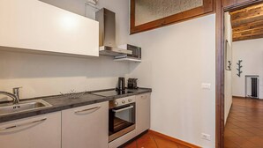 A compact kitchen with a built-in oven, a microwave, and a sink. - Maison Riva 12 Verona (Verona)