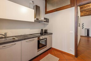 A compact kitchen with a built-in oven, a microwave, and a sink. - Maison Riva 12 Verona (Verona)