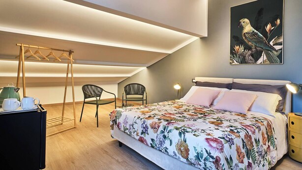 Een slaapkamer met een bed, een stoel, een hangstoel, een nachtkastje en een wanddecoratie.