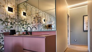 Een moderne badkamer met een roze wastafelmeubel, een grote spiegel en een wandwastafel.