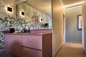 A modern bathroom with a pink vanity, a large mirror, and a wall-mounted sink. - Maison Bra 10 - Purple (Verona)