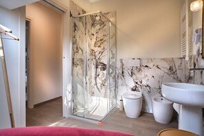 A modern bathroom with a glass shower enclosure, a white sink, and a marble backsplash. - MAISON BRA RED Verona (Verona)