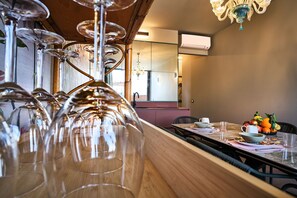 A dining area with a long wooden table, multiple wine glasses, a fruit bowl, and a chandelier. - MAISON BRA RED Verona (Verona)