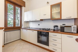 A kitchen with white cabinets, a black oven, a microwave, and a coffee maker. - -Stanza con bagno privato 3- uso cucina - Bastioni (Verona)