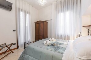 A bedroom with a bed, a wooden wardrobe, and a hanging light fixture. - -Stanza con bagno privato 3- uso cucina - Bastioni (Verona)
