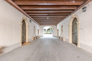 A corridor with a tiled floor, wooden beams on the ceiling, and arched doorways on both sides. - CASA MIA (Verona)