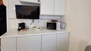 A compact kitchen with white cabinets, a microwave, and a kettle on the countertop. - Accogliente CASA DIONIGI a Verona (Verona)