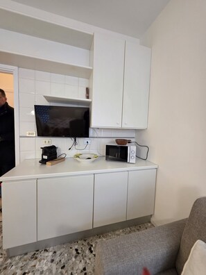 A compact kitchen with white cabinets, a microwave, and a kettle on the countertop. - Accogliente CASA DIONIGI a Verona (Verona)