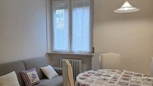 A compact living space with a sofa, a dining table, and a radiator. - Accogliente CASA DIONIGI a Verona (Verona)