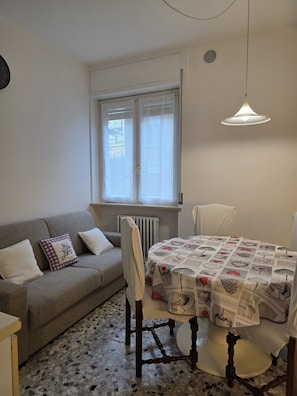A compact living space with a sofa, a dining table, and a radiator. - Accogliente CASA DIONIGI a Verona (Verona)