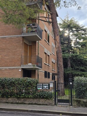 A multi-story brick building with balconies, a tree in front, and a gate with a sign. - Accogliente CASA DIONIGI a Verona (Verona)