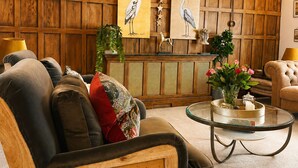 A wooden-paneled room with a sofa, a glass coffee table, and artwork on the wall. - Central Boutique 2 Bed Cottage – Sleeps 6 (Lymington)