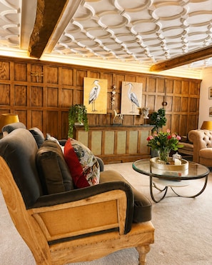 Ein Zimmer mit Holzwänden, einer Couch, einem Glastisch und Bildern an der Wand.