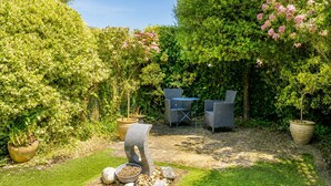 A garden with a stone table, two chairs, and a potted plant. - Central Boutique 2 Bed Cottage – Sleeps 6 (Lymington)