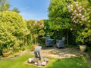 Ein Garten mit einem Steintisch, zwei Stühlen und einem Blumentopf.