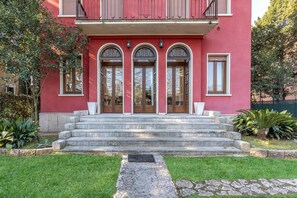 Un edificio rojo con entrada principal, una escalera y un pequeño jardín.